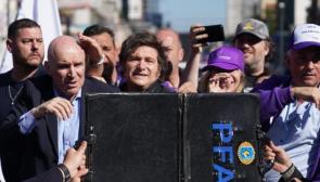 Una maleta es sostenida frente al presidente argentino Javier Milei mientras los manifestantes lanzan botellas y piedras contra el vehículo. Foto: reddit