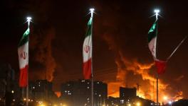 Iranian flags fly as fire and smoke from an Israeli attack on Sharan Oil depot rise. Photo: Council on Foreign Relations