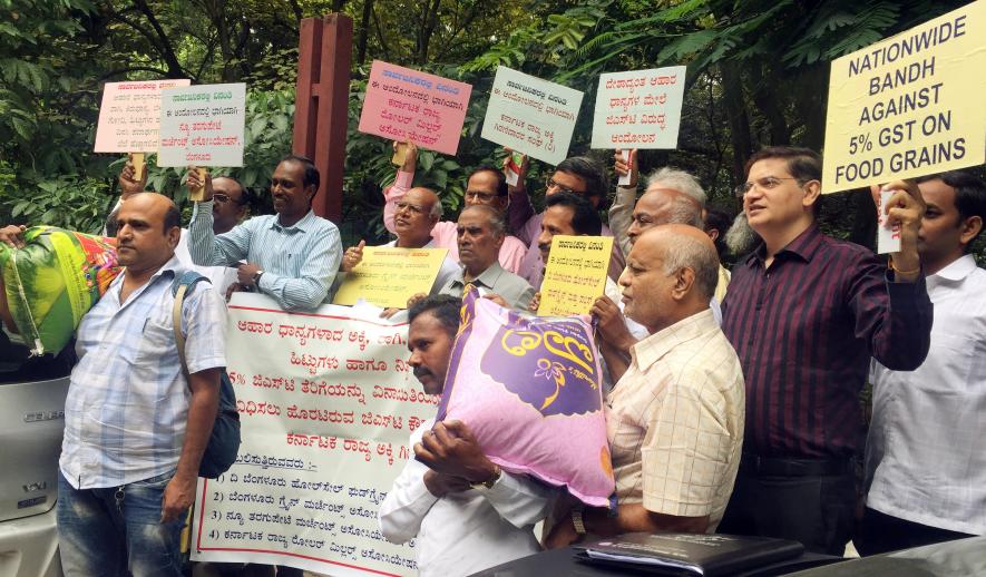 Karnataka State Rice Millers Association (KSRMA) members hold placards as they stage a protest against 5 percent GST on food grains during their press meet, at Press Club, in Bengaluru on Friday.